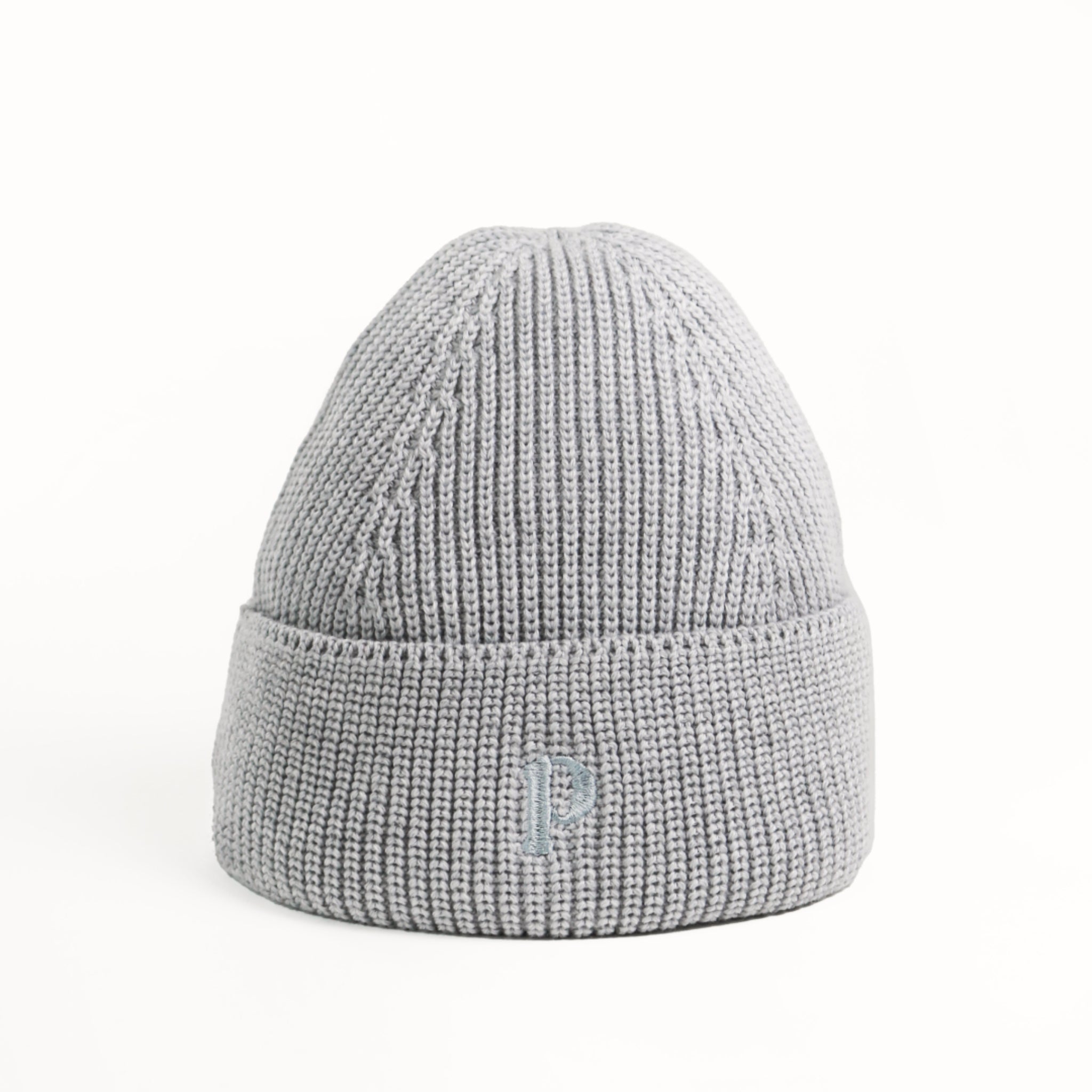 Graue Strickmütze mit umgeschlagenem Rand und einem eingestickten Buchstaben auf weißem Hintergrund.