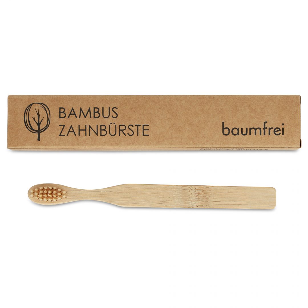Eine Bambuszahnbürste liegt vor ihrer braunen Verpackung mit der Aufschrift "Bambus Zahnbürste" und "baumfrei".