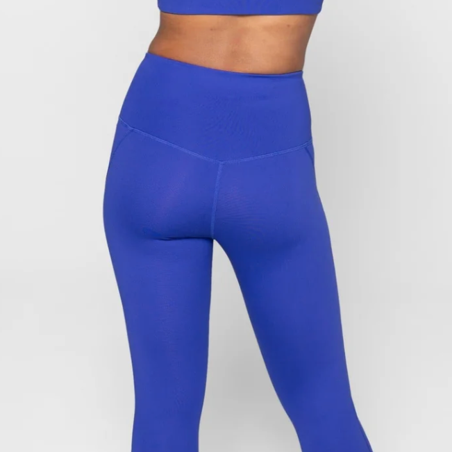 Person in blauer Sportbekleidung von hinten, trägt Leggings und ein Oberteil passend in derselben Farbe.