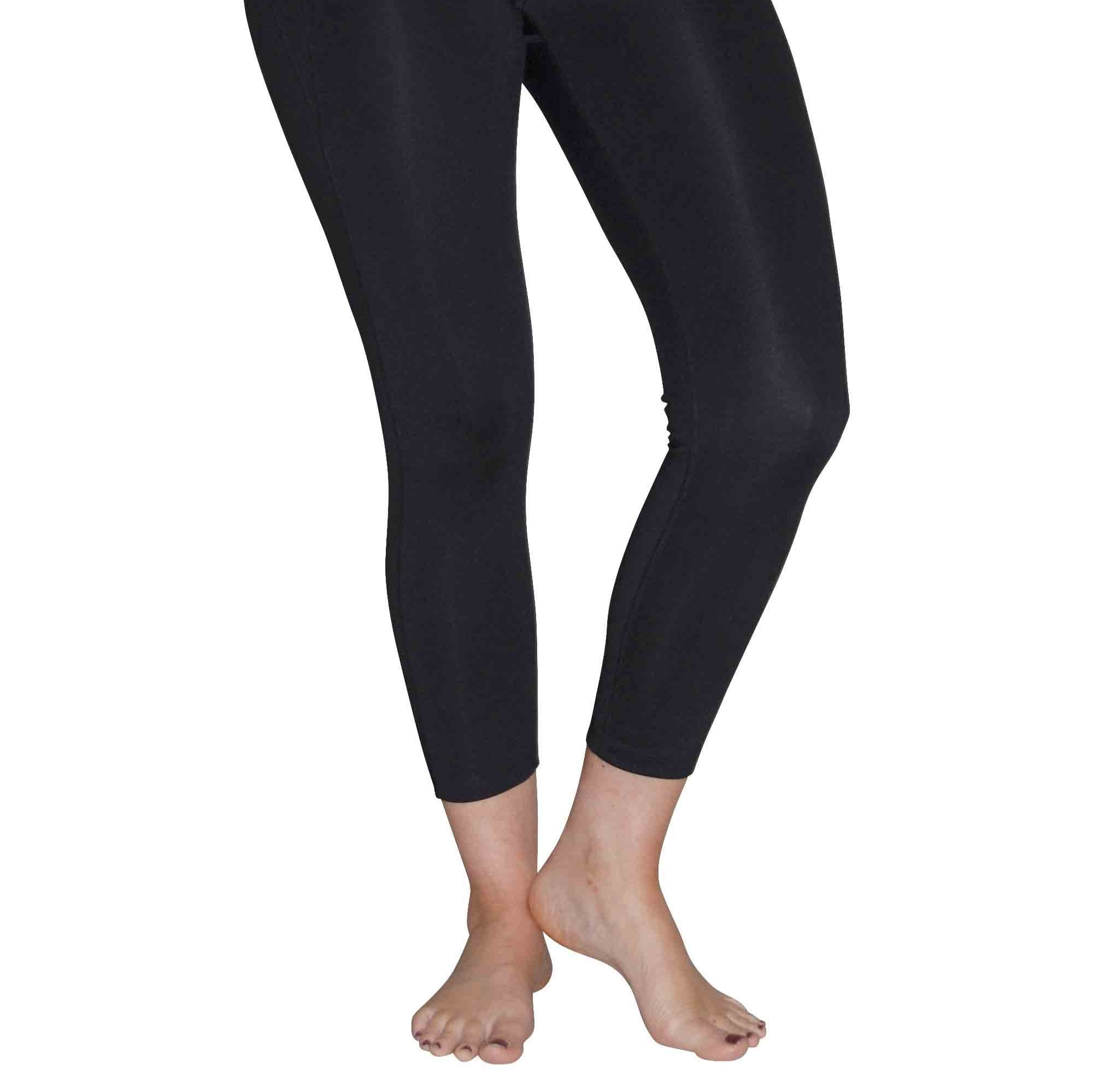 Person in schwarzen Leggings steht barfuß auf weißem Hintergrund.