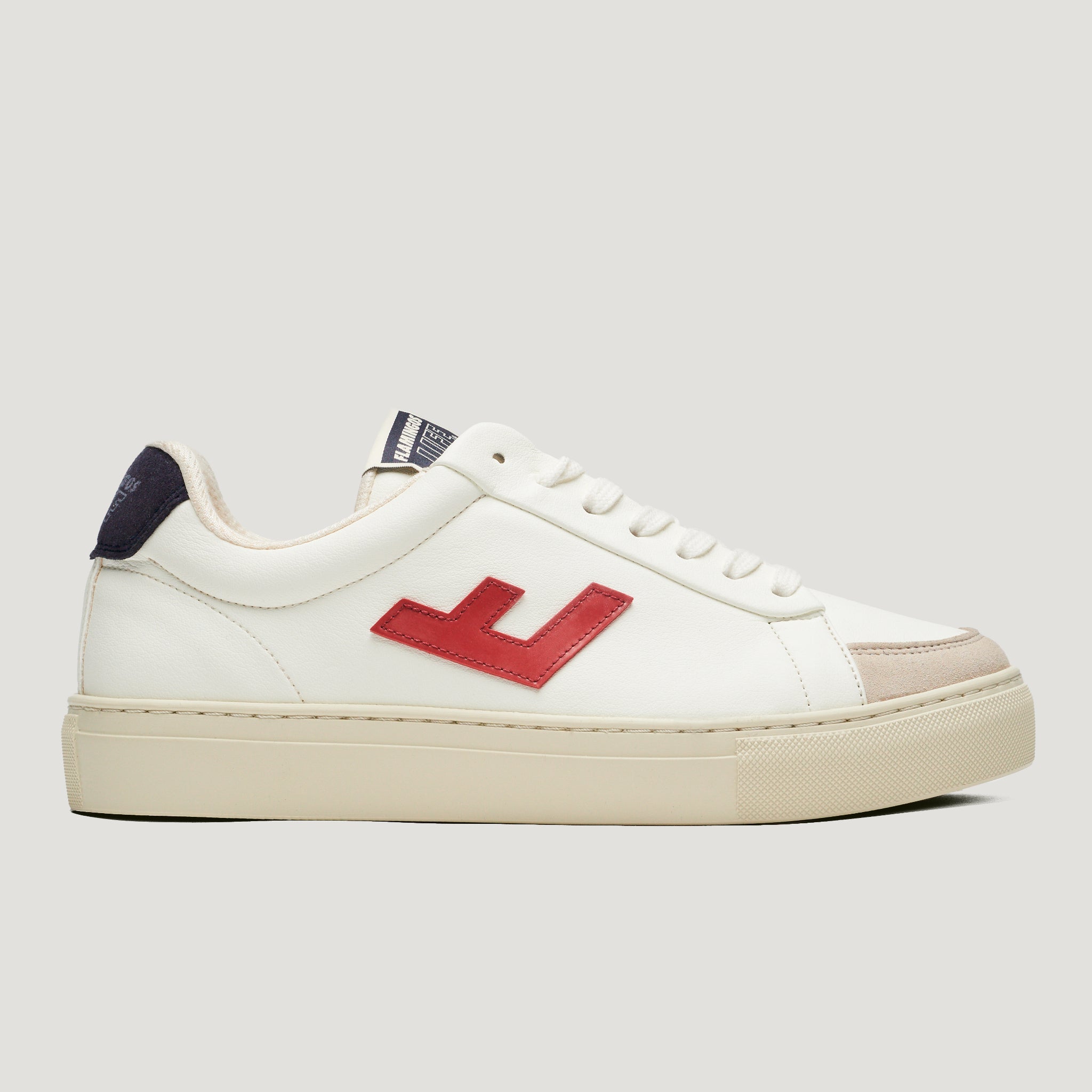 Weißer Sneaker mit rotem Logo an der Seite, cremefarbener Sohle und dunkelblauer Fersenpartie.