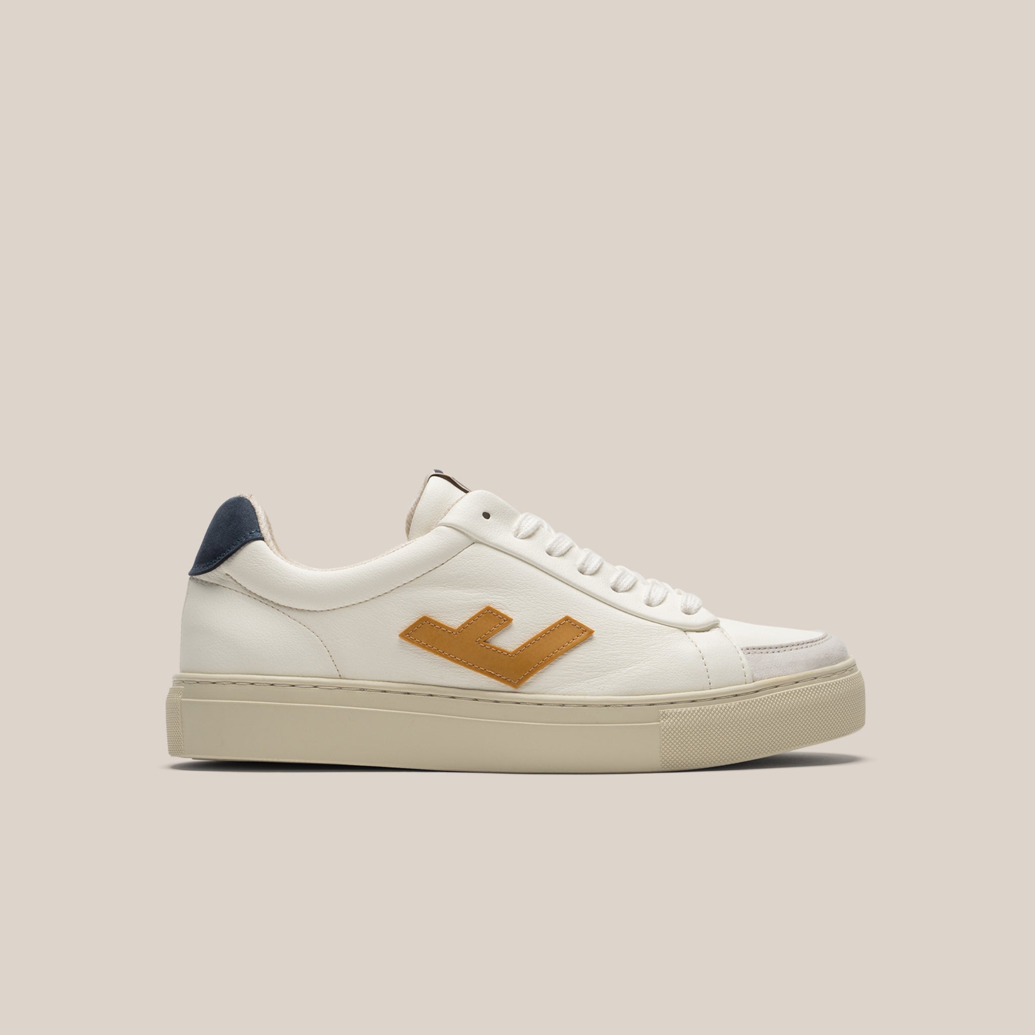 Weißer Sneaker mit dunkelblauem Detail an der Ferse und braunem Logo an der Seite vor beigem Hintergrund.