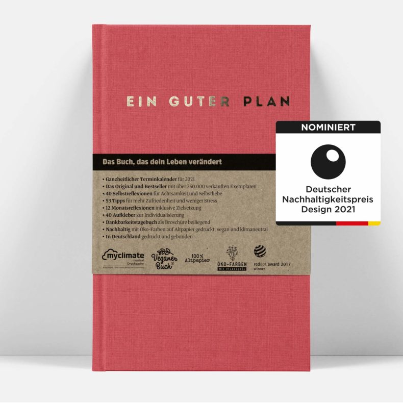 Roter Kalender „Ein Guter Plan“ mit beige Banderole, verziert mit Auszeichnungen und Nachhaltigkeitshinweisen.