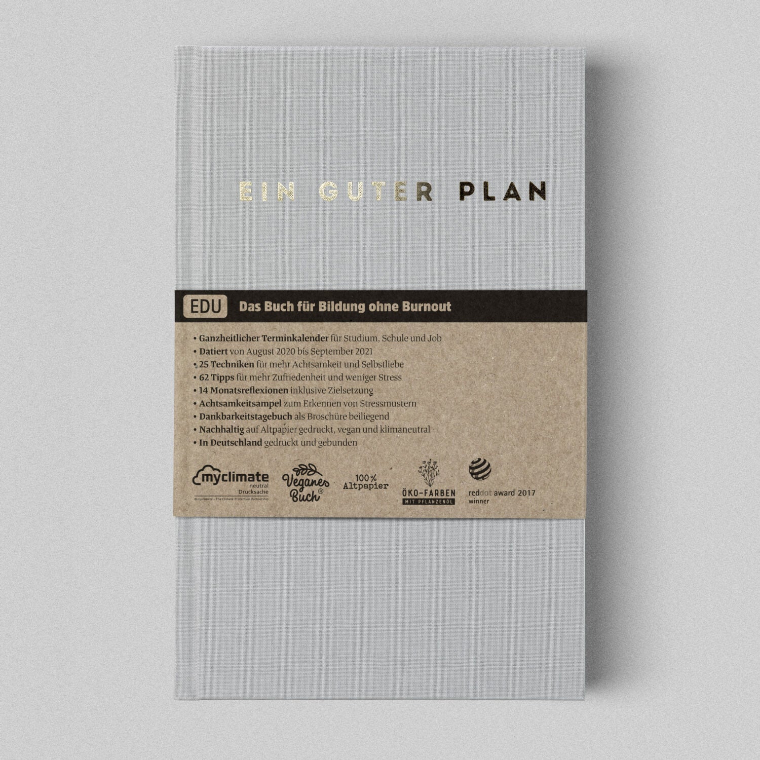Grauer Planer mit goldener Schrift "Ein guter Plan" und braunem Infoband über Bildung ohne Burnout, auf grauem Hintergrund.