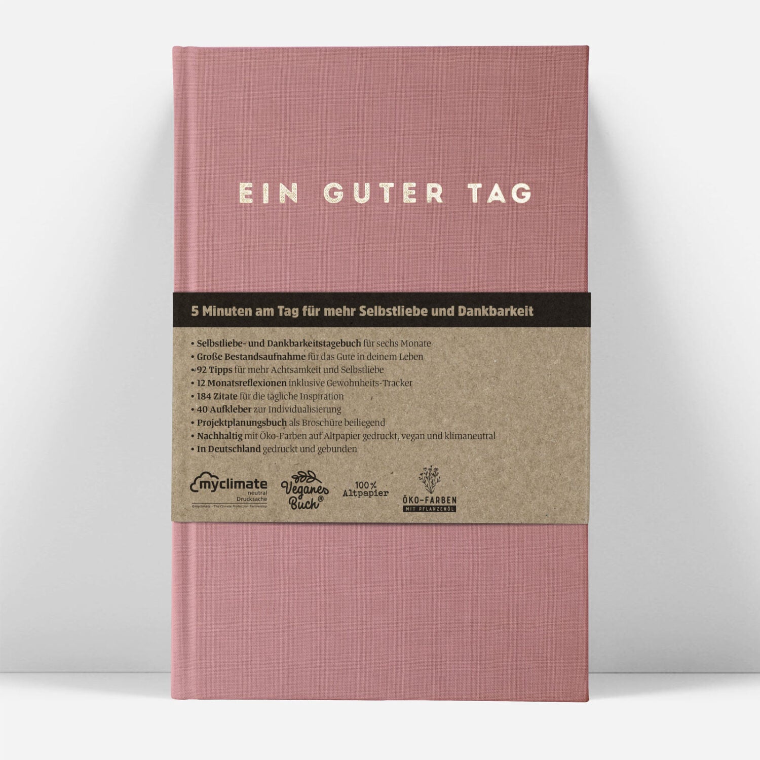 Rosa Buch mit der Aufschrift "EIN GUTER TAG" und beige Banderole mit Details auf Deutsch zur Selbstliebe und Dankbarkeit.