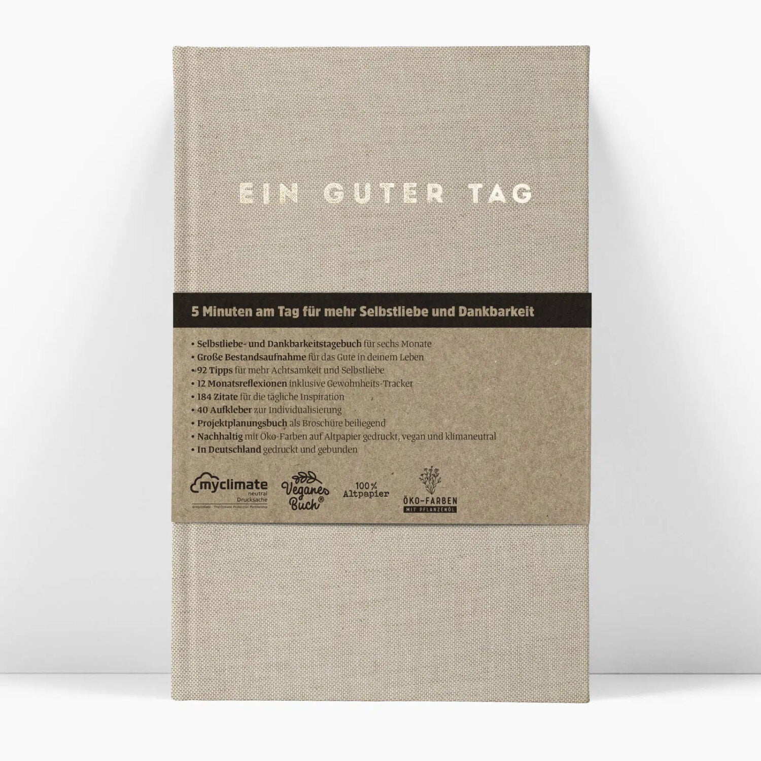 Braunes Notizbuch mit dem Titel "EIN GUTER TAG" und Details über Selbstliebe und Dankbarkeit auf dem Umschlag.