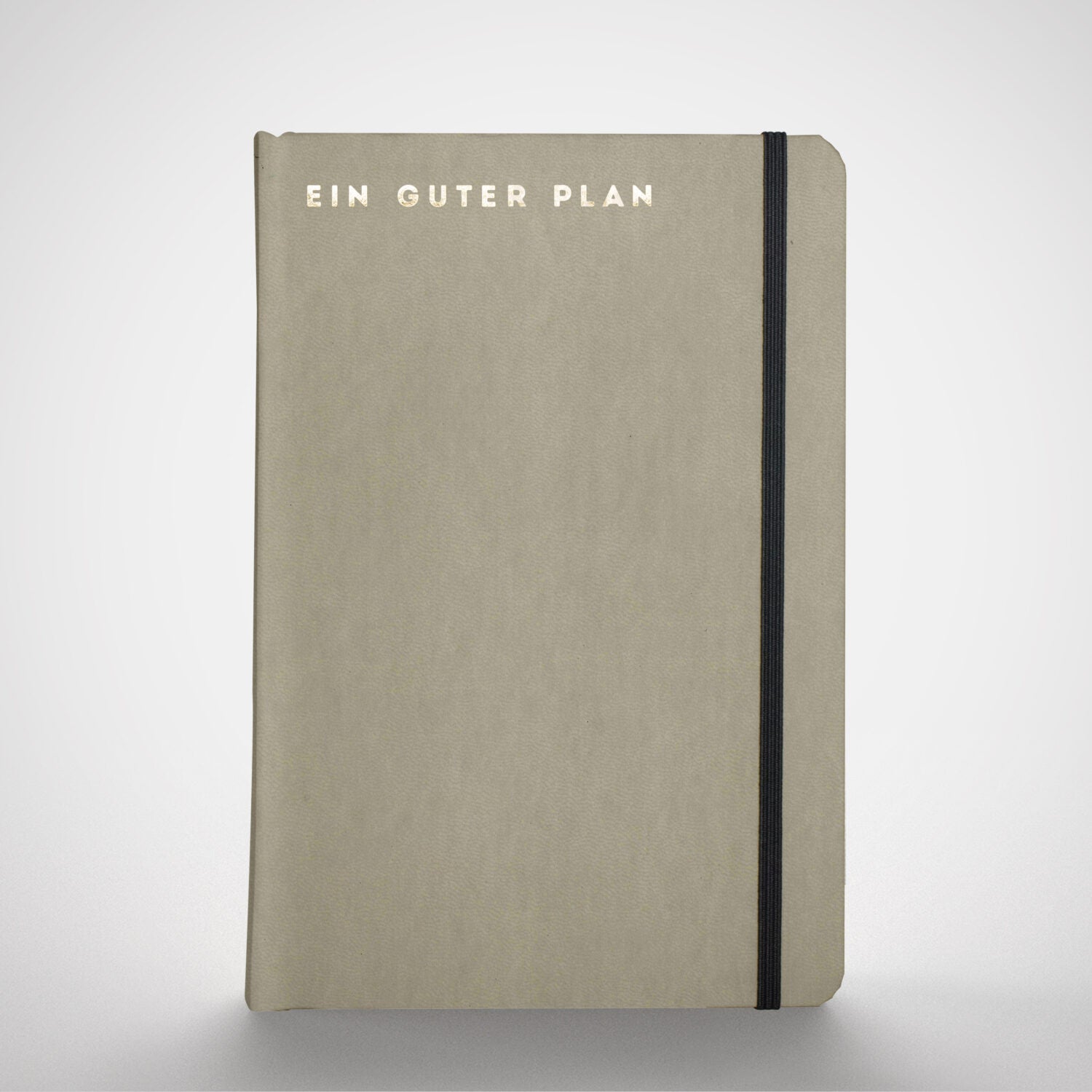 Beiges Notizbuch mit schwarzem Gummiband und der Aufschrift „Ein guter Plan“ auf dem Cover.