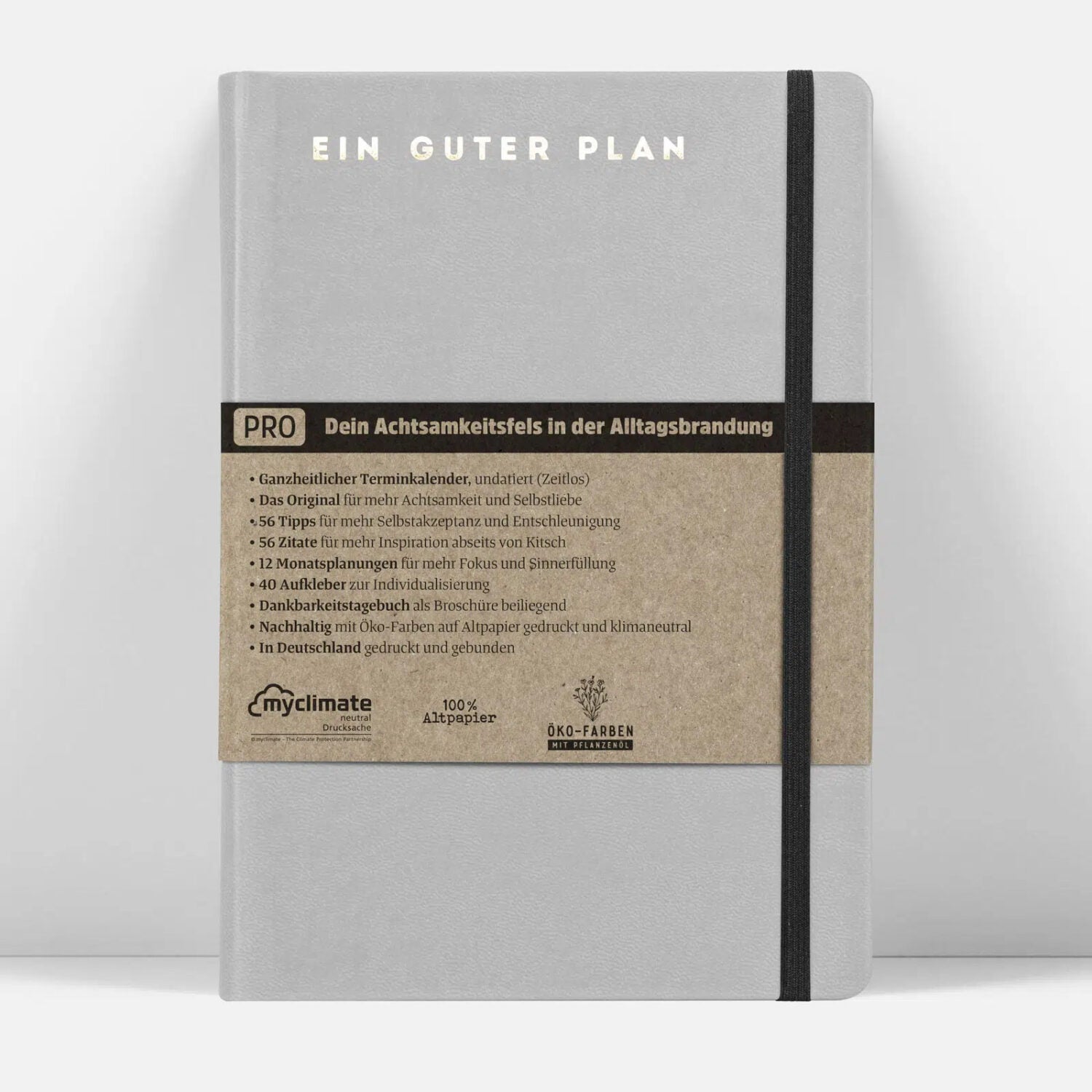 Graues Notizbuch mit der Aufschrift "EIN GUTER PLAN" und einem braunen Papierband mit Informationen zur Nachhaltigkeit.