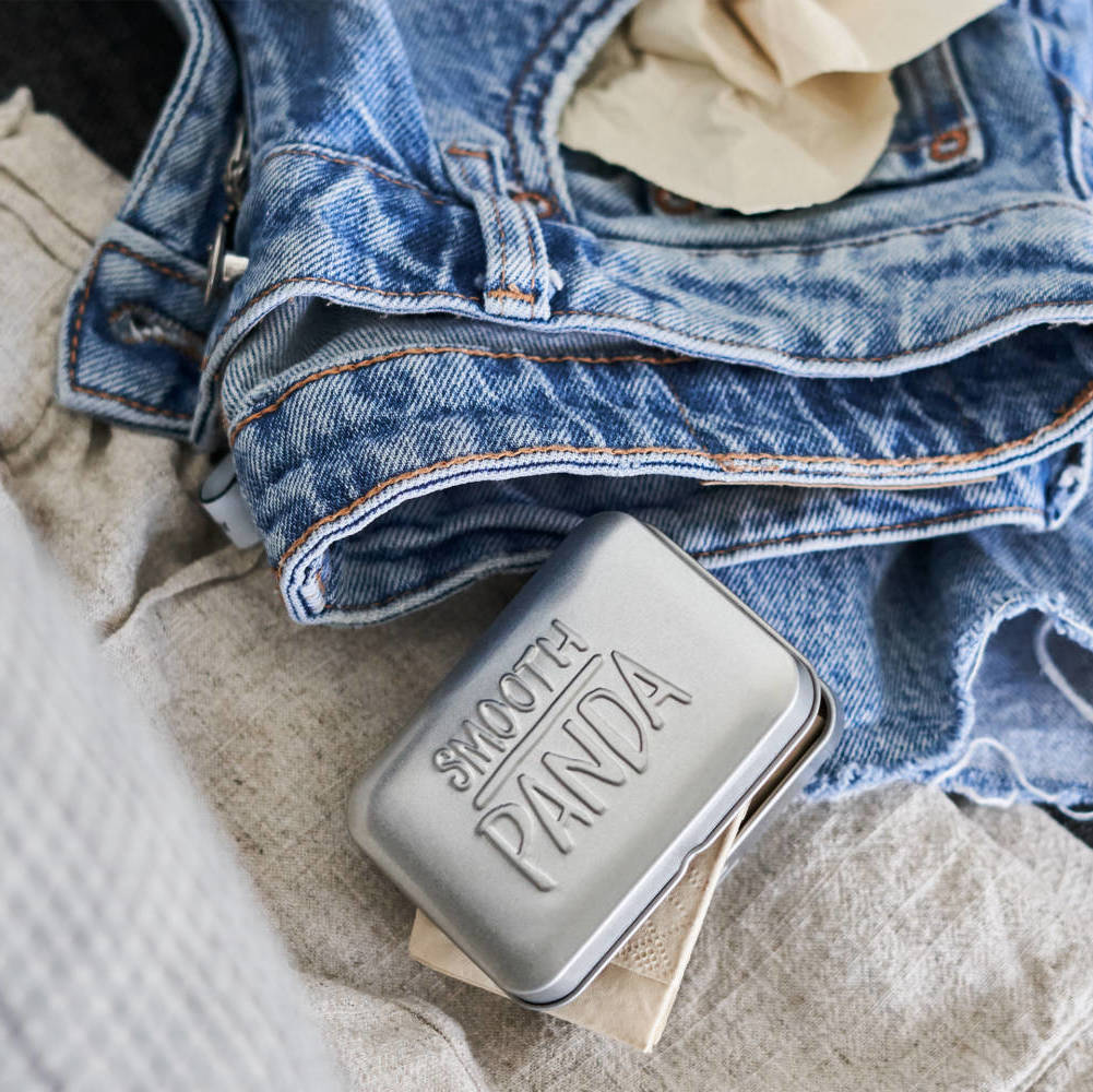 Eine Metalldose mit der Aufschrift "Smooth Panda" liegt auf einem Jeansstoff.