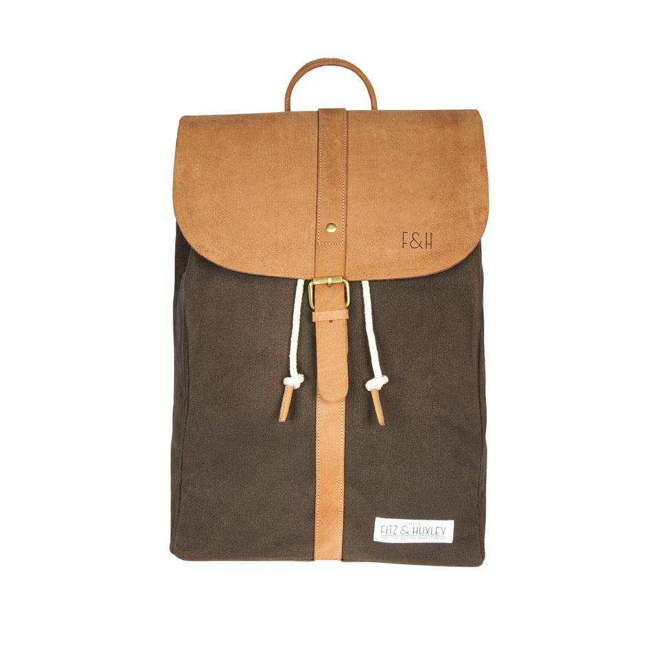 Brauner Rucksack mit Lederverschluss und Kordeldetails, gesticktem "F&H"-Logo und "Fitz & Huxley" Etikett.