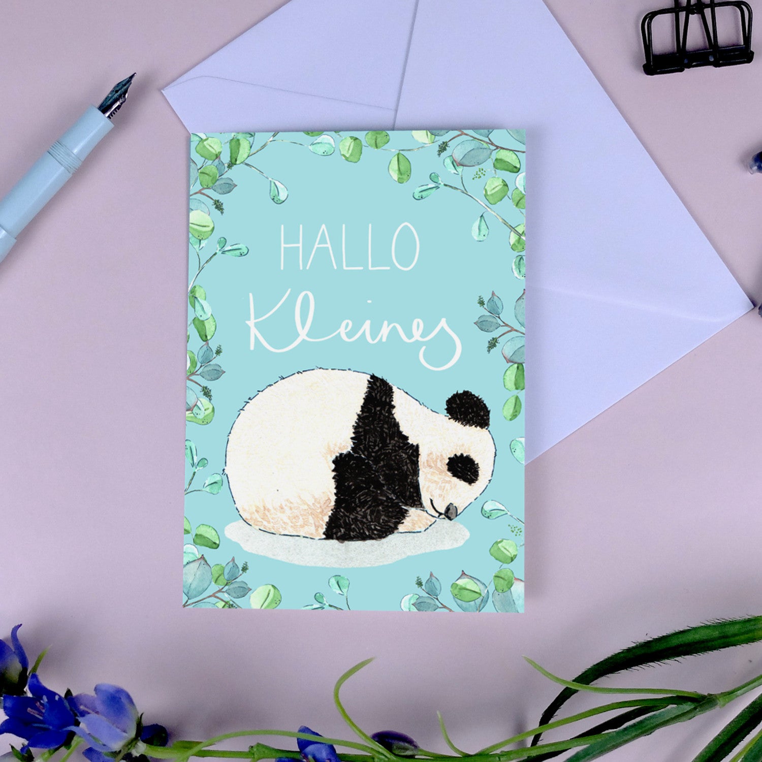 Eine Karten mit einem schlafenden Panda und der Aufschrift "HALLO Kleines", umgeben von Pflanzenmustern.