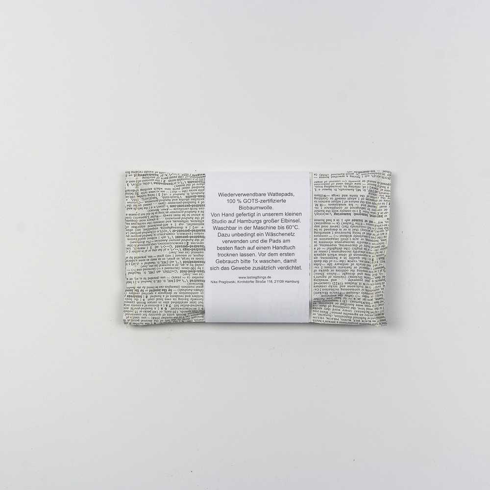 Verpackte wiederverwendbare Wattepads aus Bio-Baumwolle mit bedrucktem Textmuster auf weißem Hintergrund.