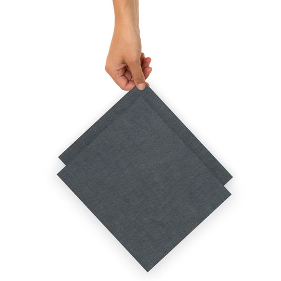 Eine Hand hält zwei übereinanderliegende dunkelgraue Stoffservietten.