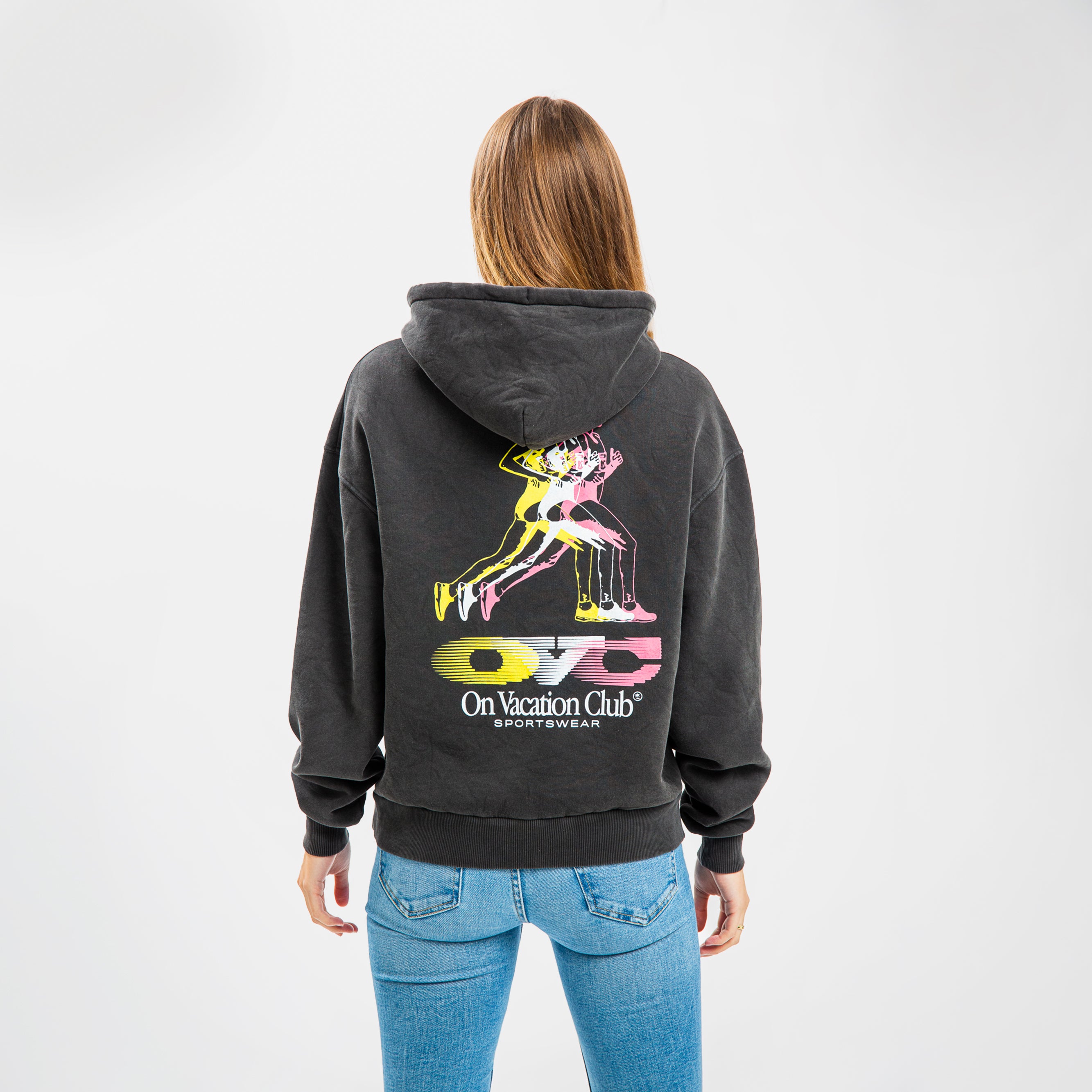 Person von hinten in schwarzem Hoodie mit buntem Läufer-Print und Jeans vor weißem Hintergrund.