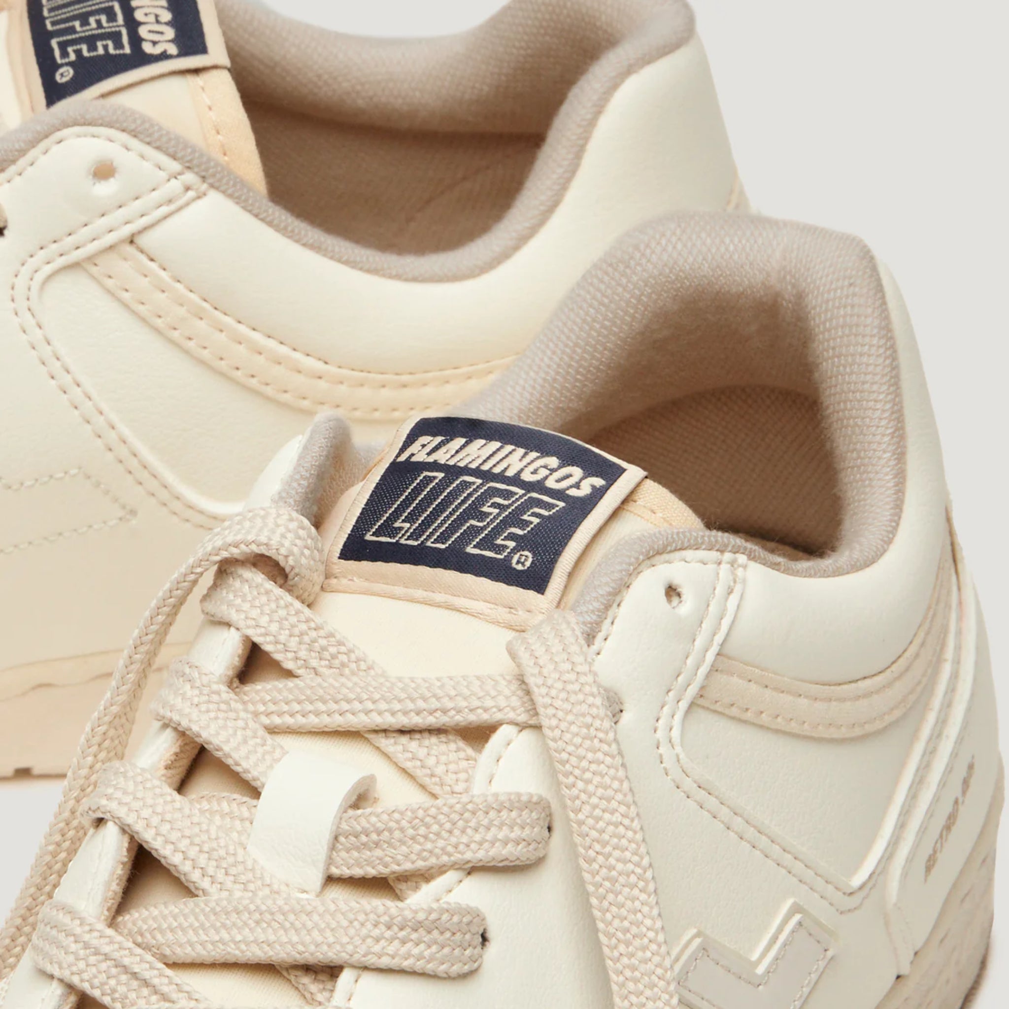 Nahaufnahme von beigen Sneakers mit dem Label "Flamingos Life" auf der Zunge.