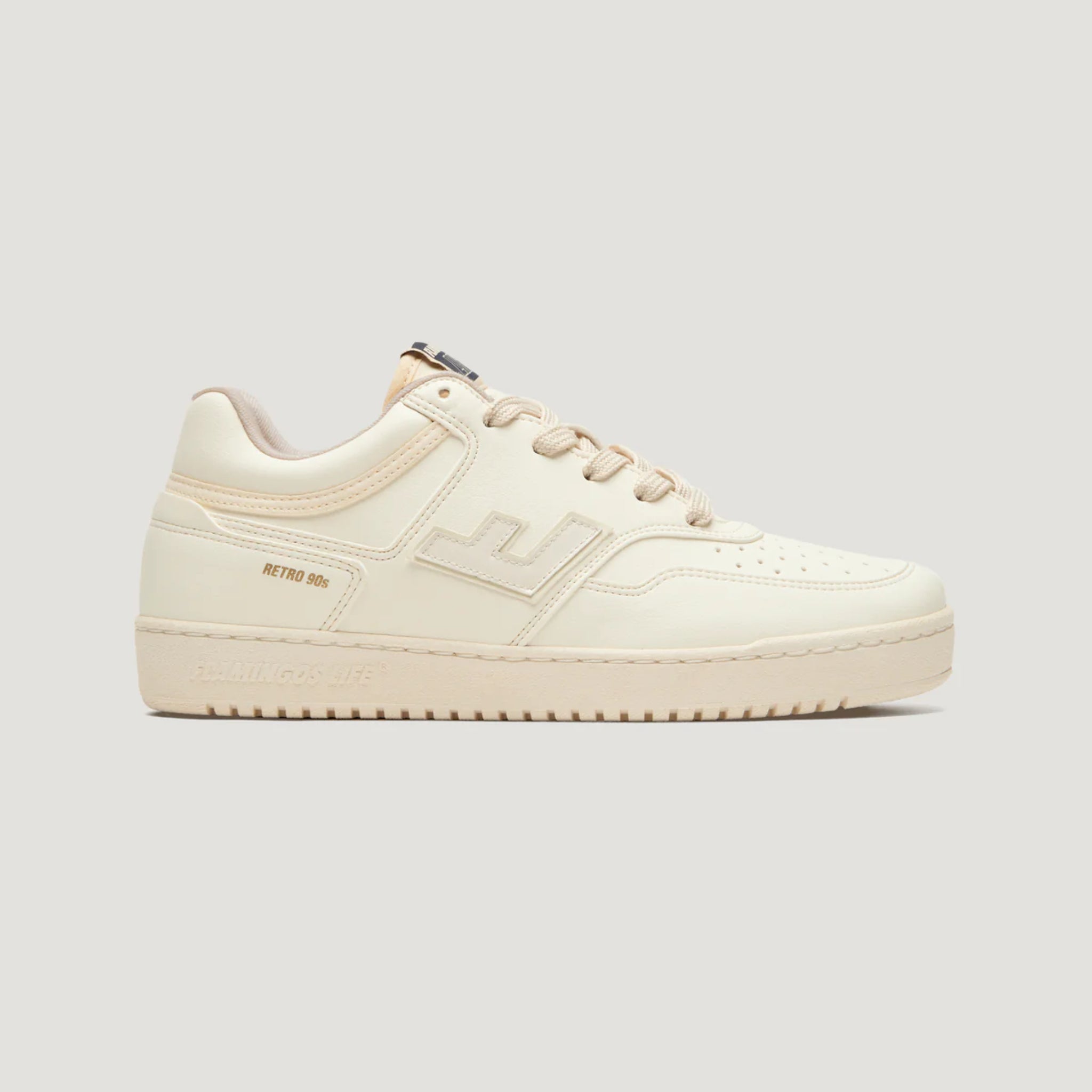Beige Sneaker im Retro-Stil der 90er-Jahre mit seitlichem Logo und gleichfarbigen Schnürsenkeln auf grauem Hintergrund.