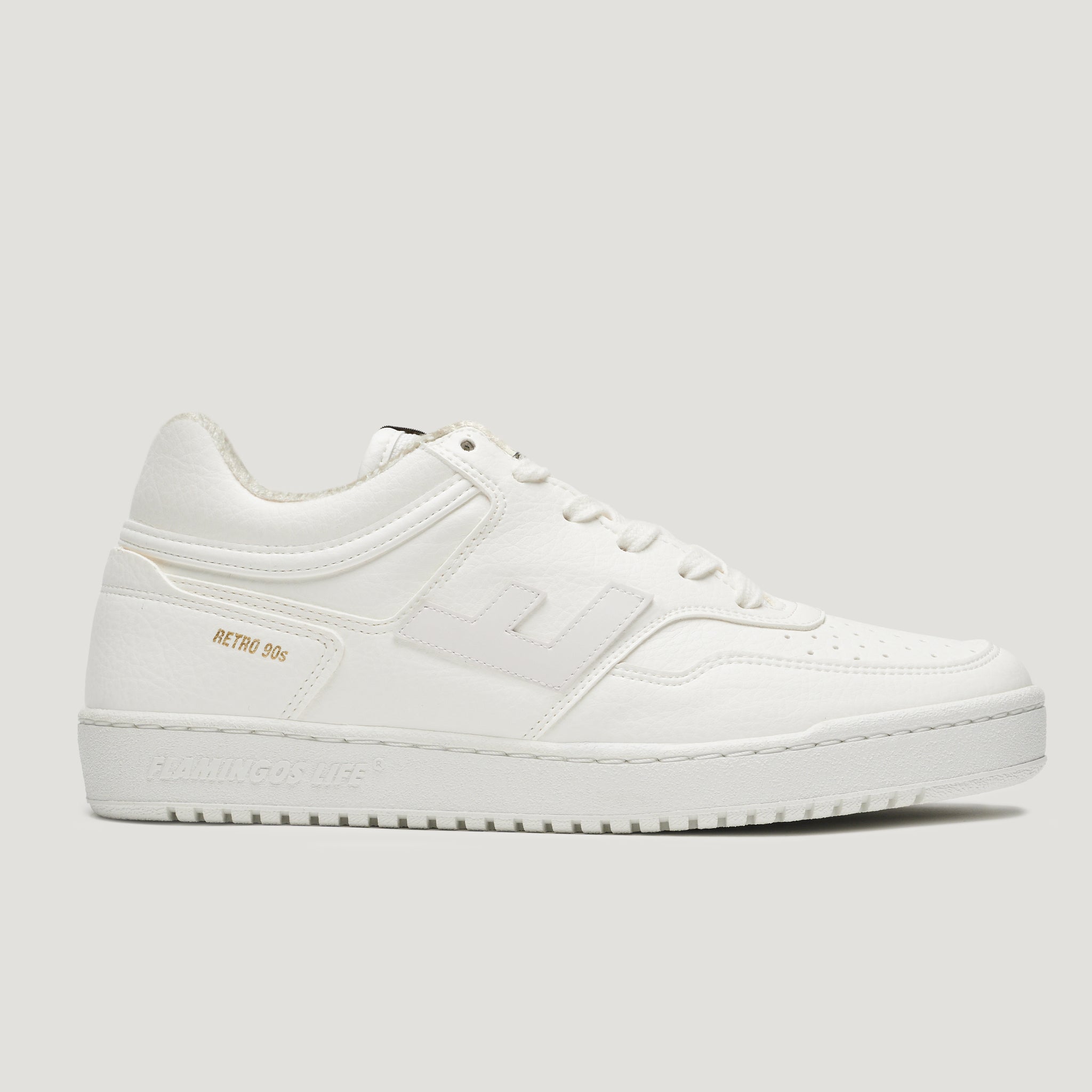 Weißer Sneaker im Retro-Design der 90er Jahre, seitlich fotografiert auf einem neutralen Hintergrund.