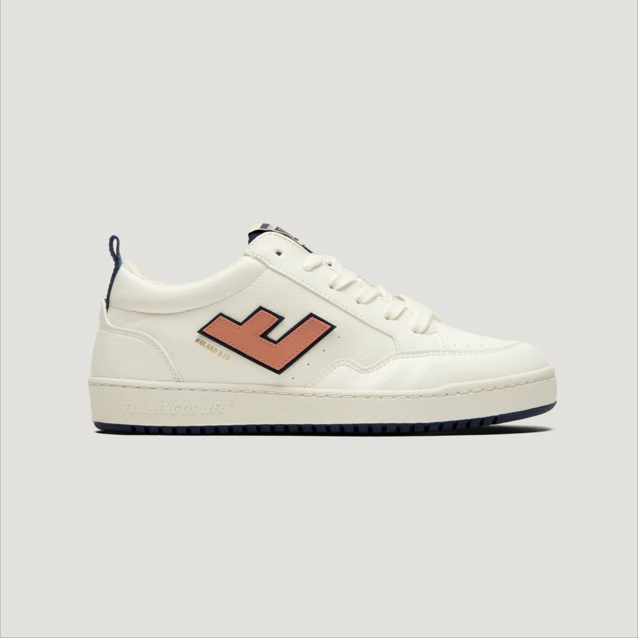 Weißer Sneaker mit dunkler Sohle und einem orangefarbenen "J"-Logo auf der Seite, vor grauem Hintergrund.