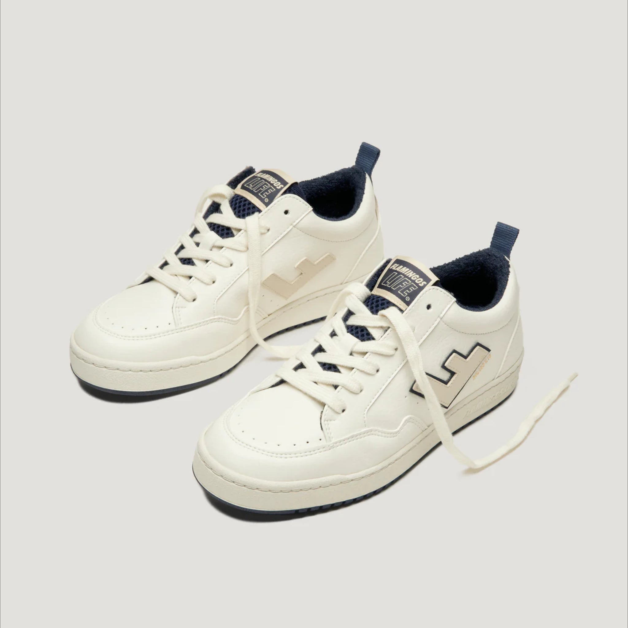 Weiße Sneakers mit blauen Akzenten auf neutralem Hintergrund, seitlich abgebildet.