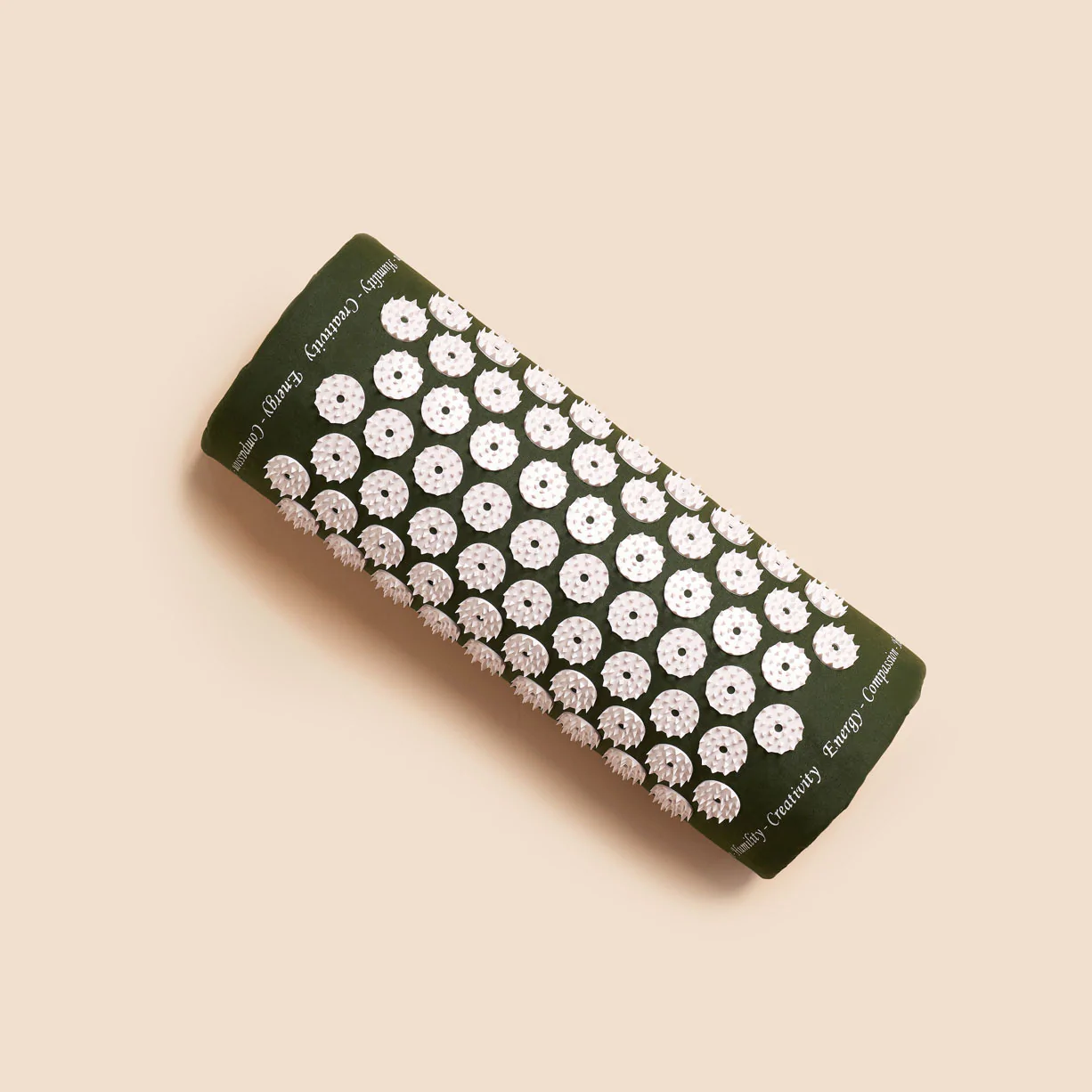 Grüne Akupressurmatte mit weißen, runden Stacheln auf hellbeigem Hintergrund.