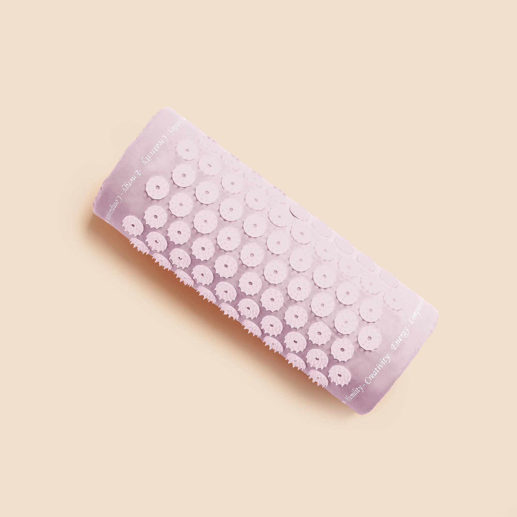 Ein rosafarbener Akupressur-Massagekissen mit stacheligen Blütenmustern auf einem beigen Hintergrund.