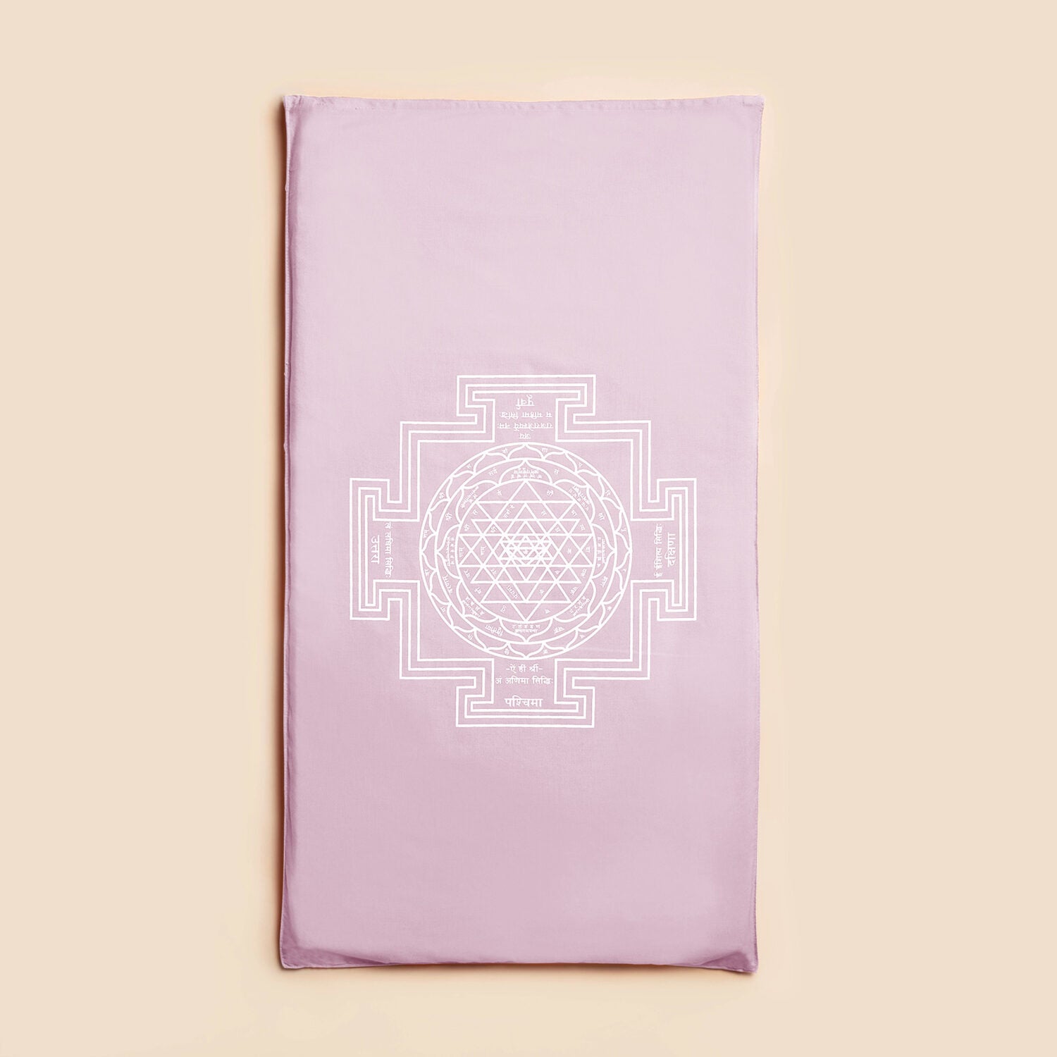 Ein lilafarbenes Kissen mit einem geometrischen weißen Sri-Yantra-Design auf beige Hintergrund.