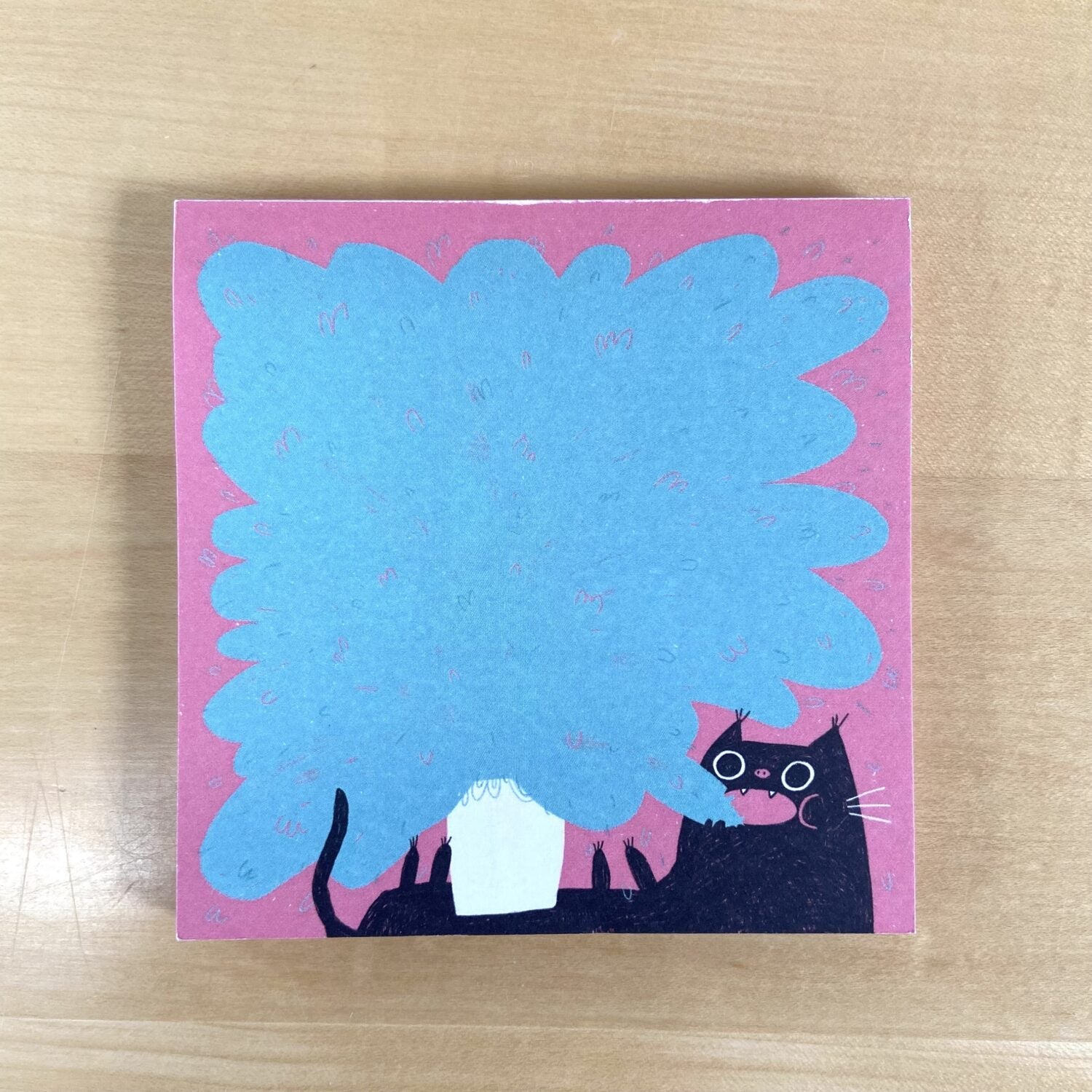 Eine Illustration zeigt eine schwarze Katze unter einem blauen Baum vor einem rosa Hintergrund.