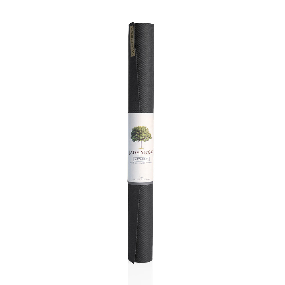 Zusammengerollte schwarze Yogamatte mit einem weißen Etikett, das einen Baum und die Aufschrift "Jade Yoga Voyager" zeigt.