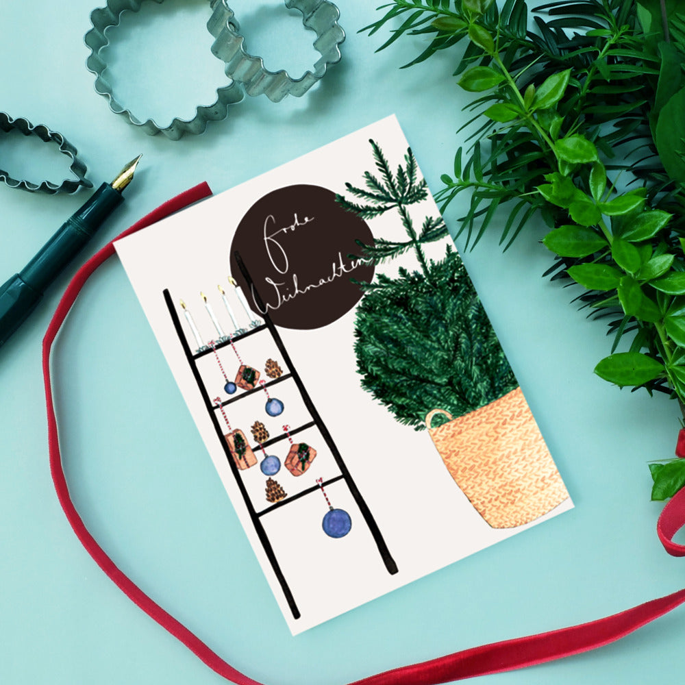 Weihnachtskarte mit Leiter als Baum, dekoriert mit Kerzen und Kugeln, daneben ein Korb mit Tannenzweigen.