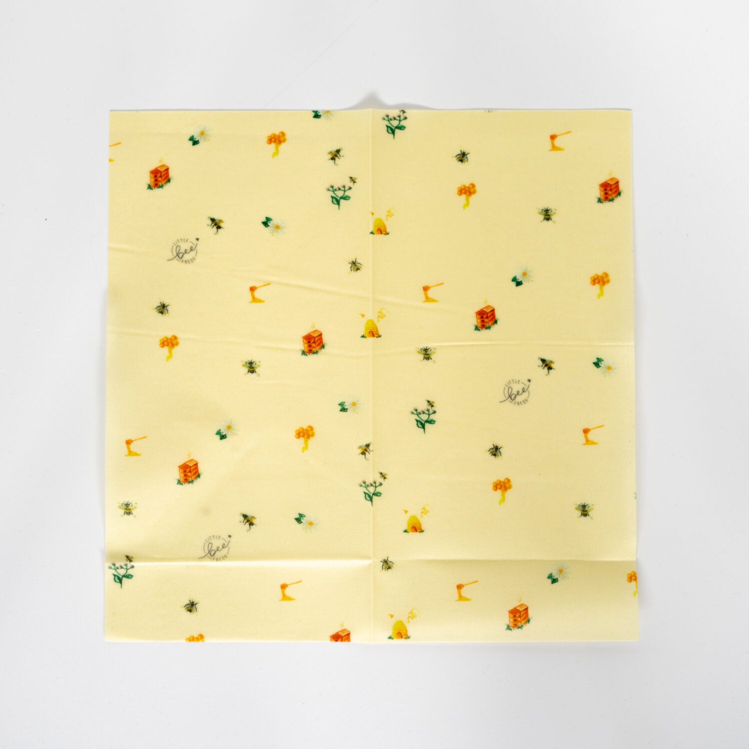 Gelbes Bienenwachstuch mit kleinen Illustrationen von Bienen, Blumen und Bienenkörben auf weißem Hintergrund.