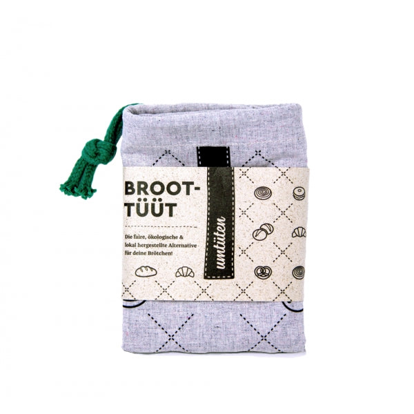 Graues Stoff-Täschchen mit grünem Stoffband, etikettiert mit "Broot-Tüüt" und Brotmuster.