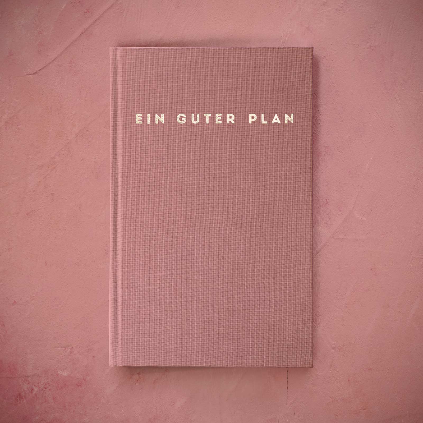 Rosa Buch mit der Aufschrift „Ein guter Plan“ auf einem rosa Hintergrund.