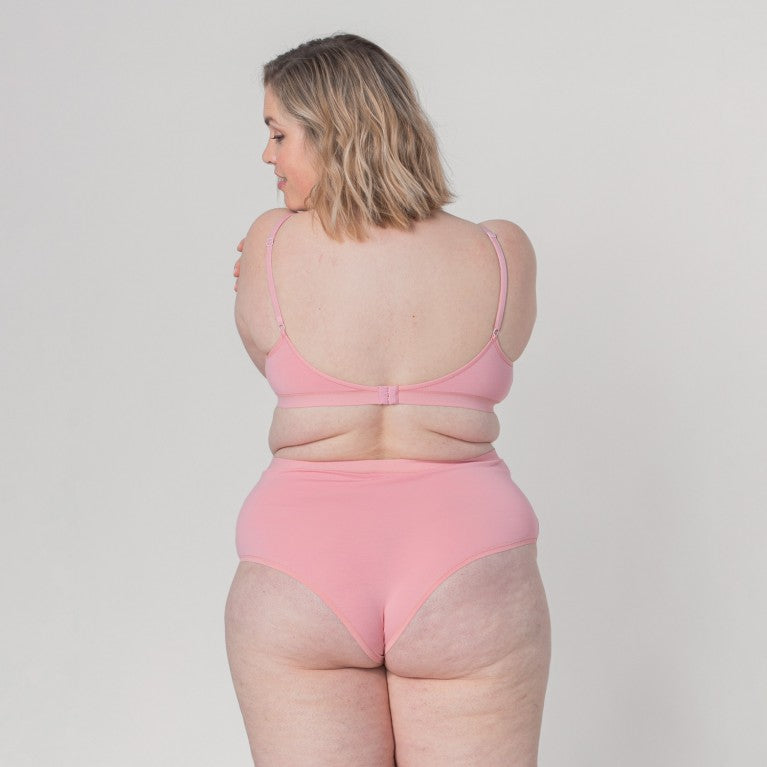 Person in pink underwear, viewed from the back, against a plain background.