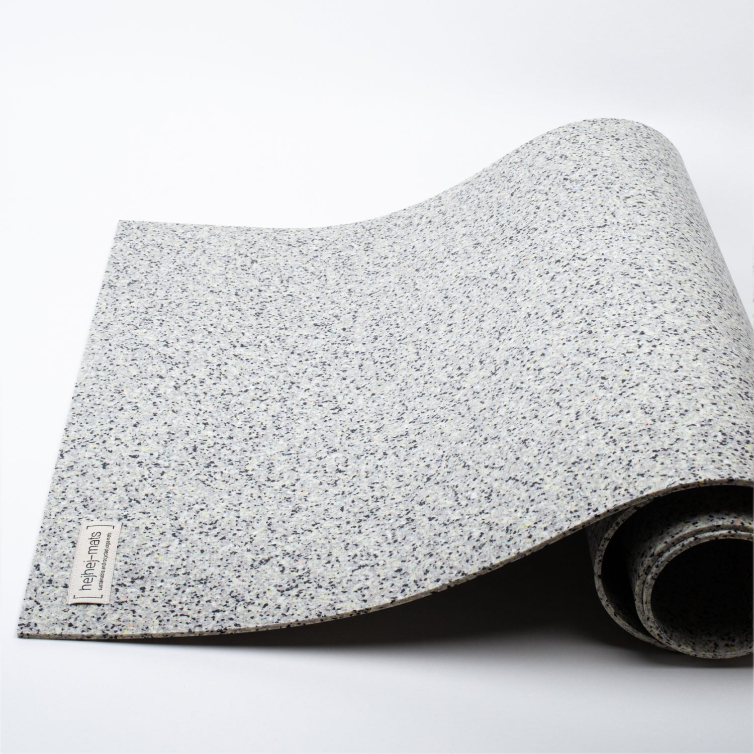 Graue Yogamatte mit gesprenkeltem Muster, teilweise aufgerollt, auf weißem Hintergrund.