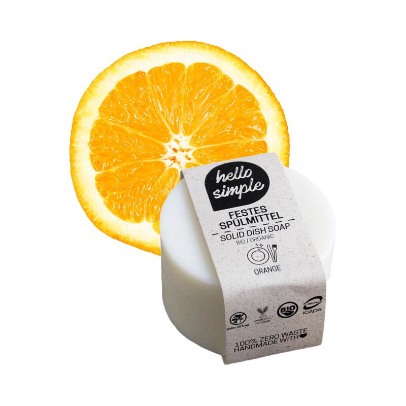 Ein festes Spülmittel mit Orangenduft vor einer halben Orangenscheibe.