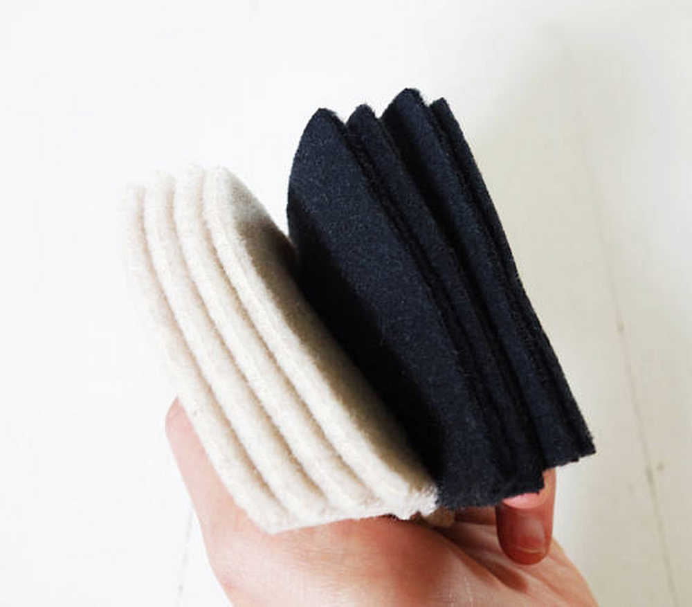 Eine Hand hält mehrere übereinandergelegte Stoffstücke in Weiß und Schwarz.