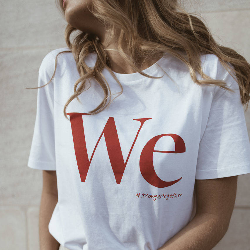 Person in a white T-shirt with red "We" and "#strongertogether" text, looking to the side against a light background.