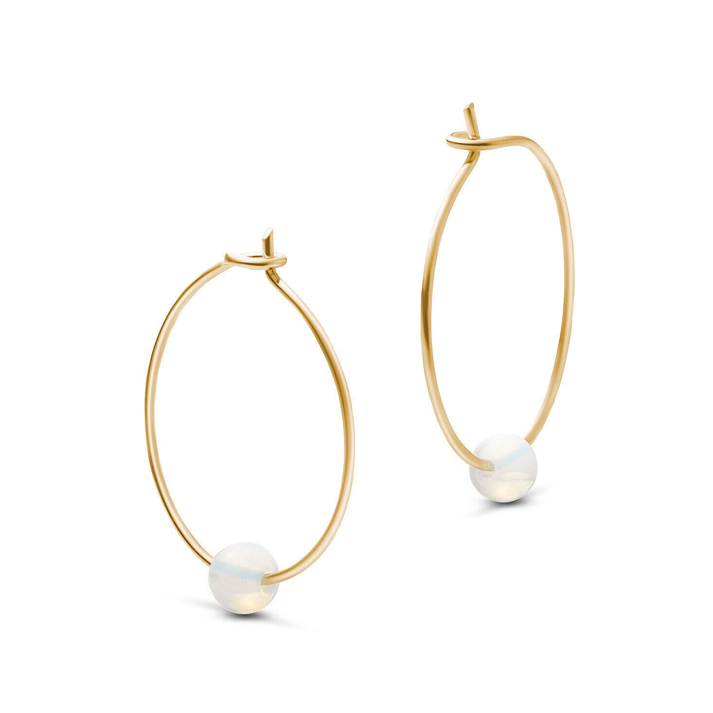 Goldene Kreolen mit einem schwebenden, schimmernden weißen Stein an der Unterseite.