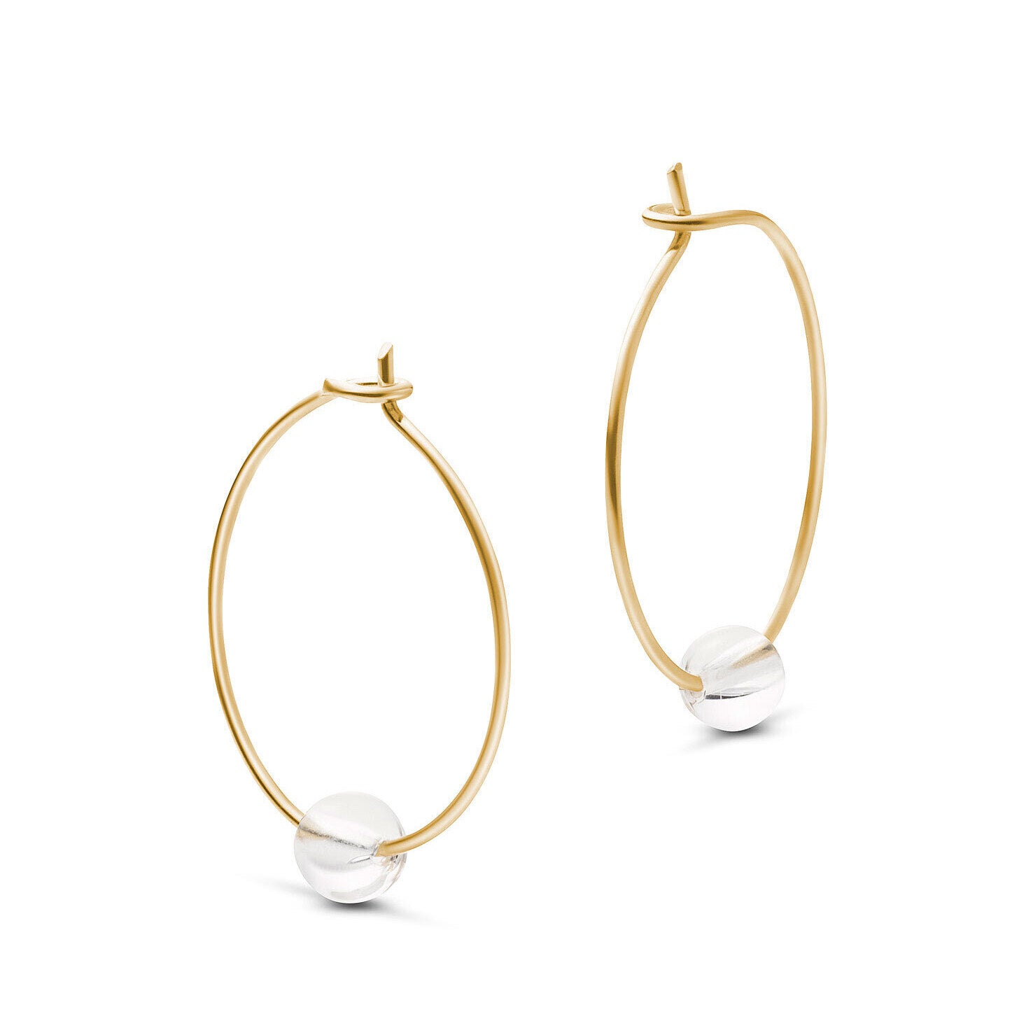 Goldene Creolen mit einer Silberkugel an der Unterseite vor weißem Hintergrund.