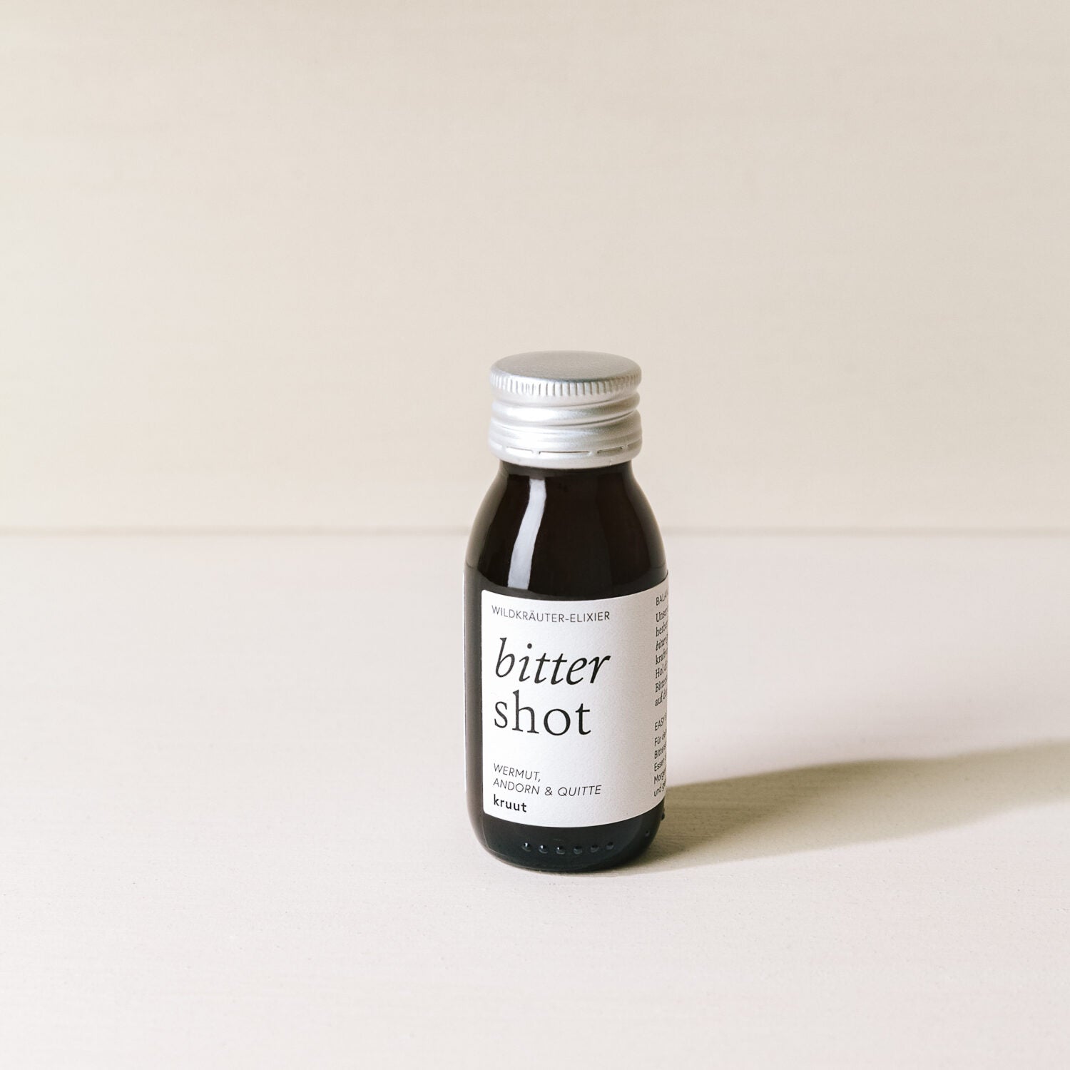 Kleines Glasfläschchen mit der Aufschrift "bitter shot" auf einem hellen Hintergrund.