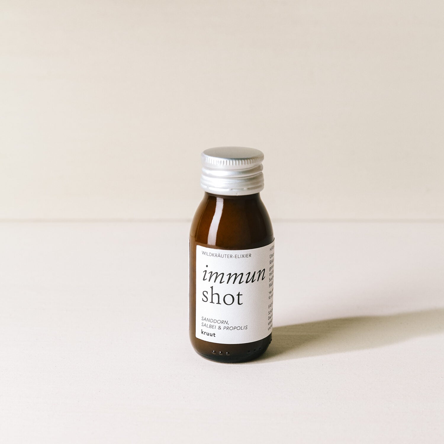 Braune Flasche mit silbernem Deckel, darauf ein Etikett mit der Aufschrift "immun shot" und Zutaten wie Sanddorn.