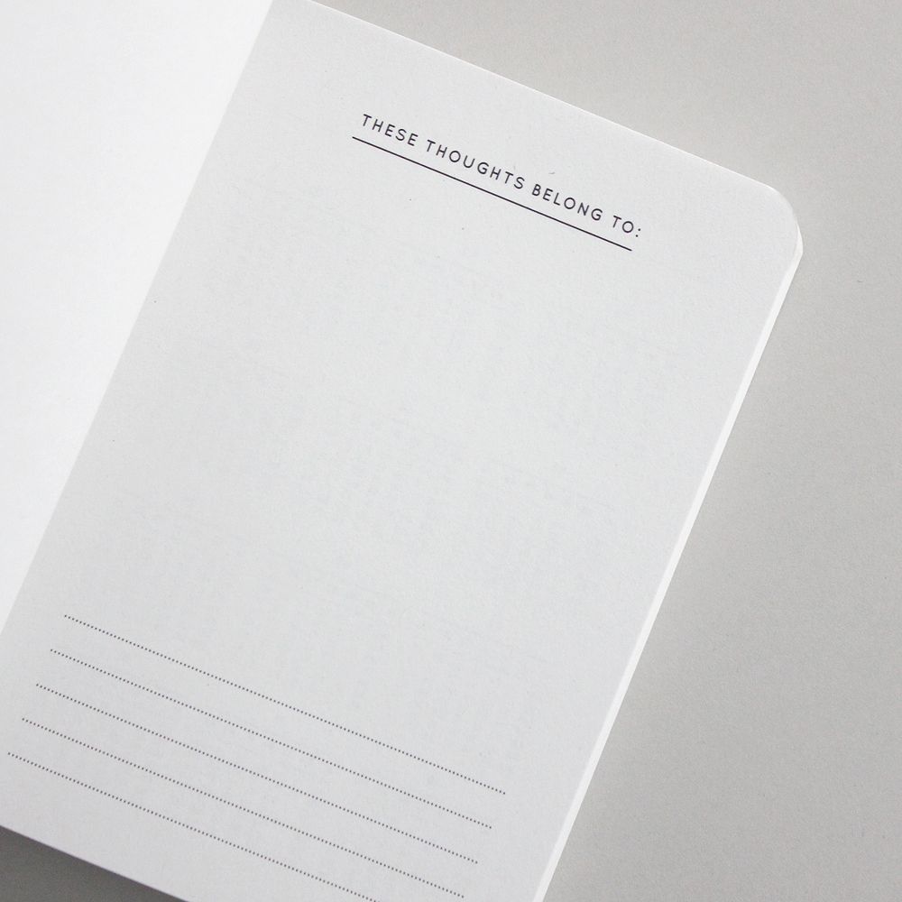 Offene Seite eines Notizbuchs mit der Überschrift "These Thoughts Belong To" und leeren Linien darunter.