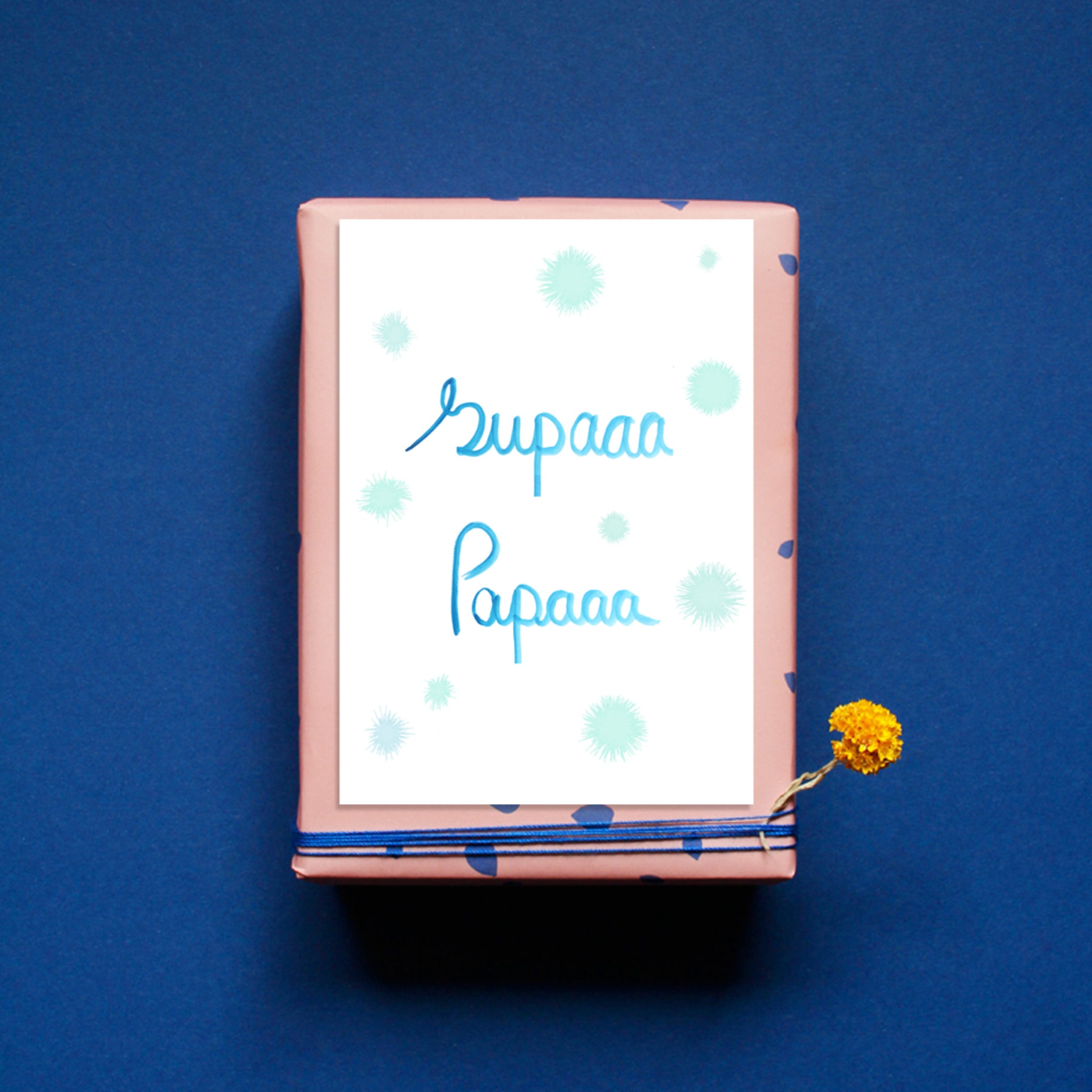 Geschenk mit rosa Papier und blauen Punkten verpackt, gelbe Blume an der Seite, Schriftzug "Supaaa Papaaa" auf Karte.
