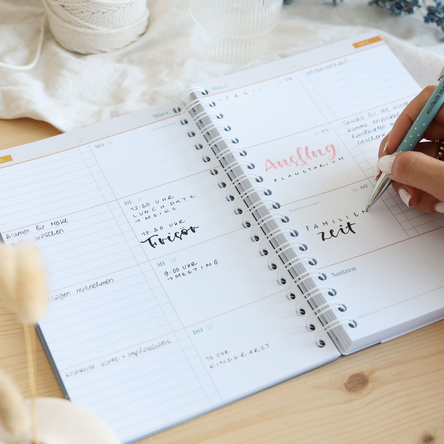 Eine Person schreibt in einen Planer mit Spiralbindung.