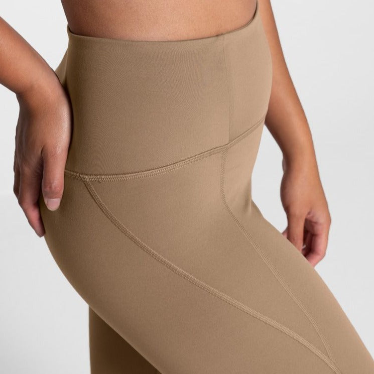 Nahaufnahme einer Person in hautfarbener, nahtloser Sport-Leggings, eine Hand an der Hüfte.