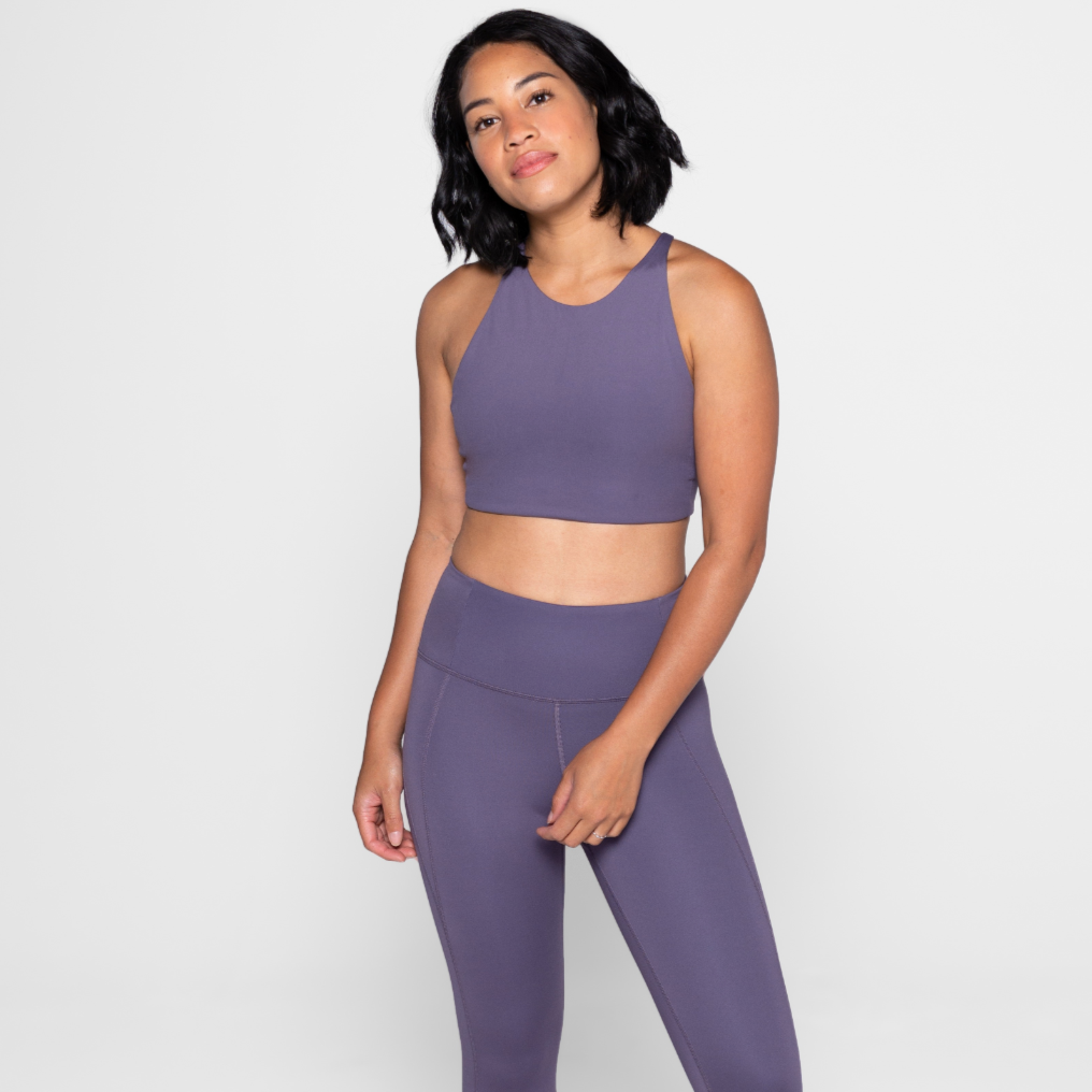 Eine Person in lila Sportkleidung steht vor einem neutralen Hintergrund.