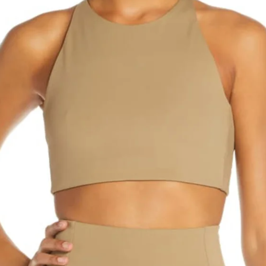 Person in beige, ärmellosem Crop-Top mit Rundhalsausschnitt.