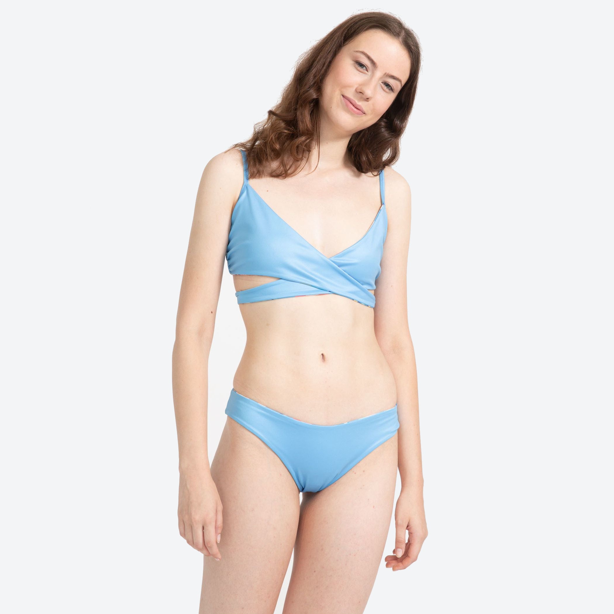 Person in einem blauen Bikini auf hellem Hintergrund posierend.