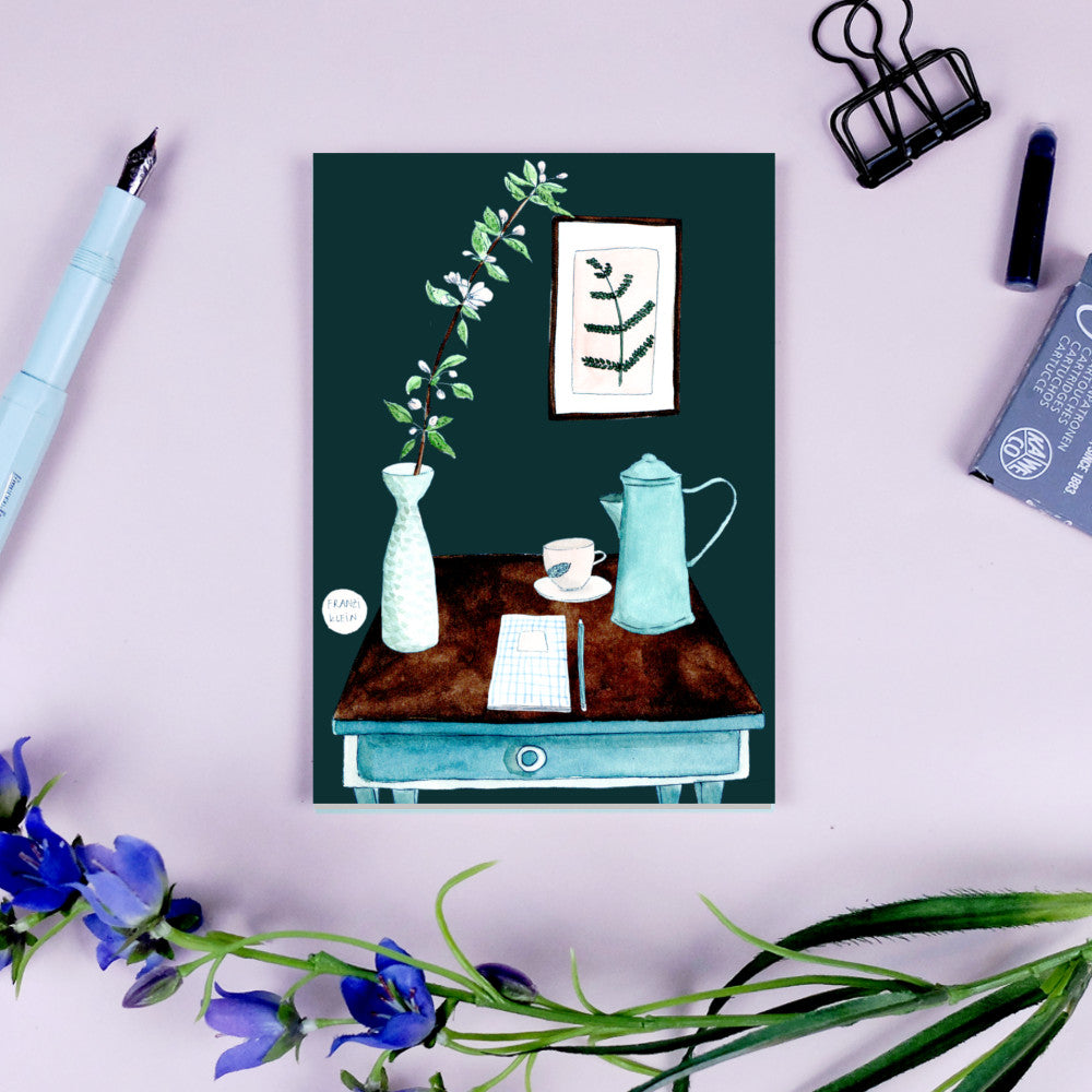 Ein Schreibtisch mit Vase, Kaffeekanne, Tasse und Notizbuch, umgeben von Blumen und Schreibutensilien.