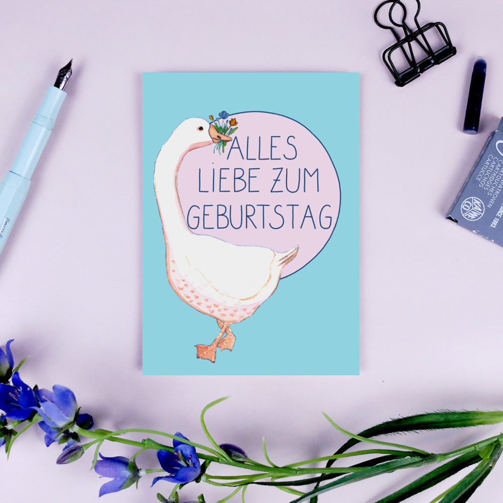 Geburtstagskarte mit Gans, die Blumen hält und "Alles Liebe zum Geburtstag" auf pastellblauem Hintergrund.